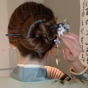 Detail view of butterfly hair pin with purple resin flowers and elegant metal tassels