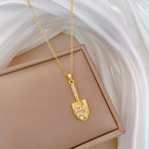 Detailed macro view of a gold shovel pendant with sparkling pavé crystals on a silk cloth
