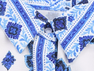 Detalle del cuello de solapa con estampado floral azul y botón en el vestido de algodón