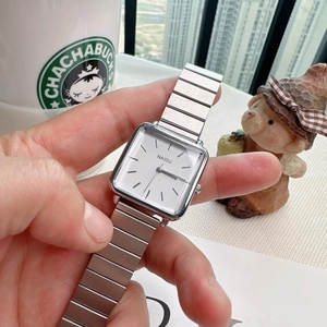Detail shot of a square quartz watch with silver metallic expansion band on wrist