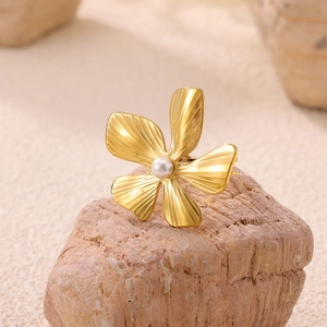 Macro detail of a golden flower ring with a white pearl on a natural textured rock