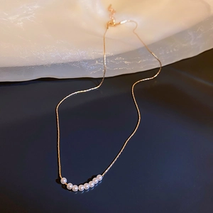 Detailed view of elegant gold pearl necklace on reflective blue surface background