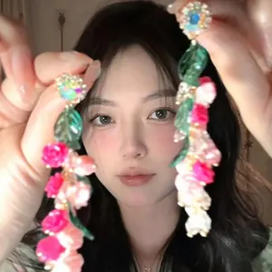 Close-up of long floral drop earrings with pink acrylic flowers and green leaves