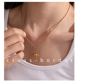 Detail view of a 18K gold plated stainless steel cross pendant necklace on a model