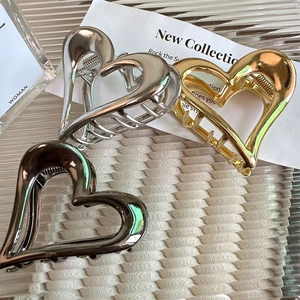 Detail of hollow heart metal hair claws in gold, silver and gun black finishes