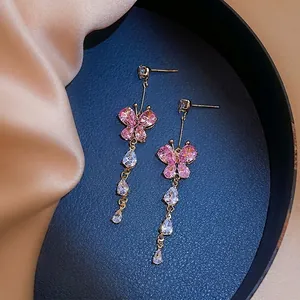Detail of elegant gold butterfly tassel earrings with pink crystals and zircon stones