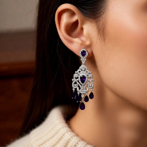 Detail of luxury silver floral drop earrings with purple teardrop crystals on ear