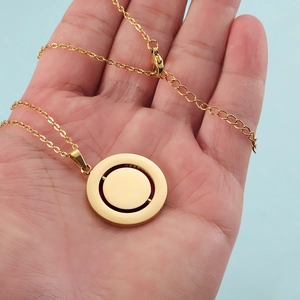 Gold stainless steel rotating round pendant necklace with concentric circles on palm