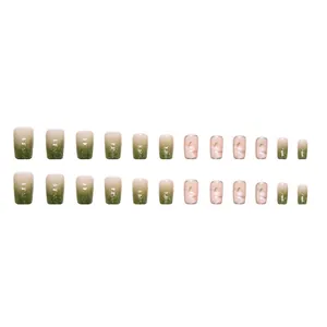 Faux ongles dégradés vert et blanc avec motifs de camélia blanc et paillettes douces