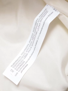 Macro shot of product care label showing 100% cotton material in multiple languages