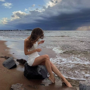 Close-up of a white ribbed knit mini dress worn on rocks by the seaside landscape