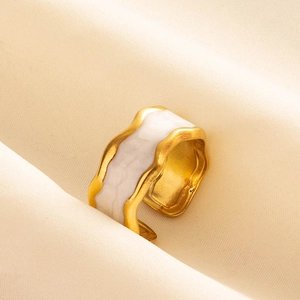 Detail of gold-plated open ring with irregular wave pattern and white enamel finish