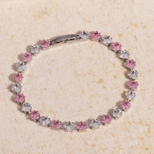 Detail of pink and white square-cut zircons set in a silver tennis bracelet on beige fabric