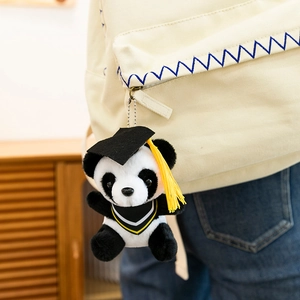 Detailed view of a graduation panda plush keychain hanging on a beige canvas backpack