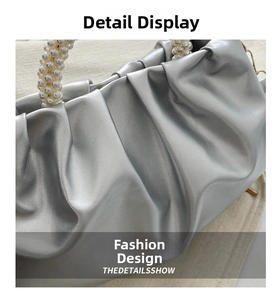 Detailed close-up of silver pleated handbag featuring a textured pearl bead handle