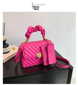Detail of rose red quilted crossbody bag with pleated cloud handle and heart lock