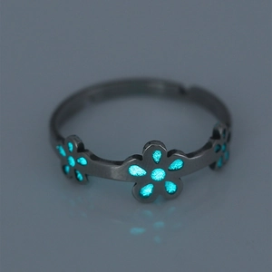 Macro view of adjustable black ring with glowing blue flower petals in the dark