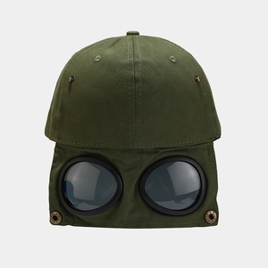Detail of army green cargo baseball cap featuring integrated aviator goggles and brass studs