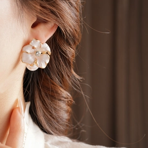 Détail de boucles d'oreilles fleurs vintage avec bord doré, émail et centre en cristal