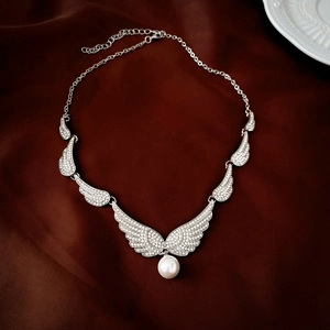 Detailed macro view of silver angel wing necklace with clear rhinestones and a white pearl