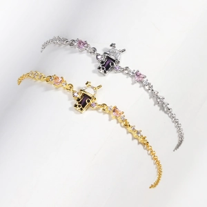 Detail of milk tea cup charms with pink hearts and zircons on gold and silver bracelets