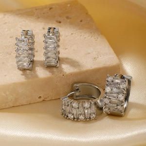 Macro detail of silver hoops with inlaid cubic zirconia on stone and gold silk background