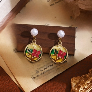 Detail of floral enamel earrings with pearls hanging against a vintage background
