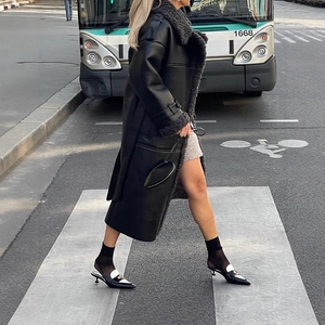 Chic black longline shearling coat with plush lapels and belt in urban street setting