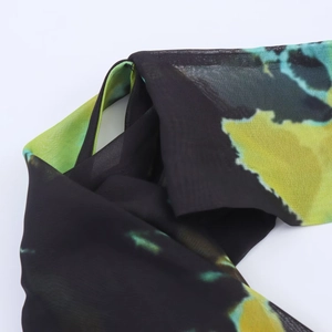 Gros plan sur un tissu mousseline tie-dye léger avec des motifs noirs et verts