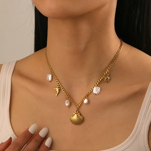 Gold-plated necklace featuring scallop and dolphin pendants with a white pearl on a model