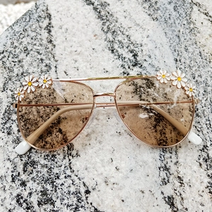 Detail of kids gold metal aviator sunglasses with white daisy floral decorations