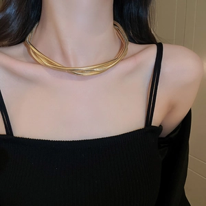 Close-up of a layered gold snake chain necklace with a metallic twisted design on a model