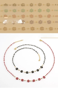 Detail of bohemian floral bead necklace with red and black crystals and 18K gold chain