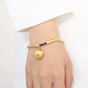 Detailed view of minimalist gold bead pendant on black woven cord bracelet worn by model