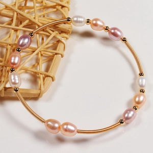 Macro detail of multicolored freshwater pearls and golden spring coil on handmade bracelet