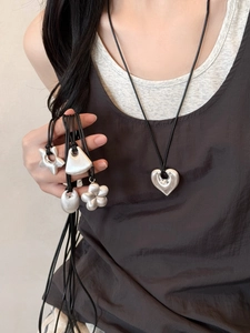 Detail of silver matte pendants with heart and star shapes on black wax cords necklaces