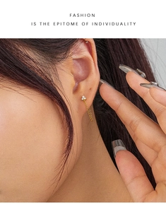 Detailed view of gold chain tassel earring with sparkling white zircon stone accents