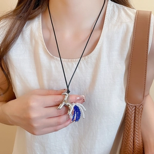 Detailed close-up of a silver pony pendant with blue and white beads on a black cord