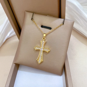 Close-up of a gold cross necklace with sparkling zircons in a brown jewelry gift box