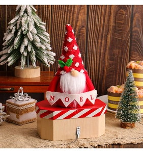 Detailed view of a Christmas gnome sitting on a candy box holding a NOEL banner