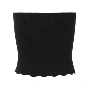 Detalle de un top de punto acanalado negro con dobladillo ondulado sobre un fondo blanco