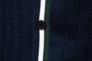 Dettaglio del cardigan in maglia blu scuro con bottone nero e bordo a contrasto