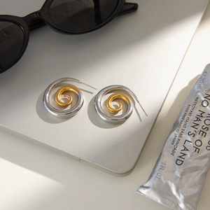 Two-tone spiral textured stainless steel hoop earrings on a grey laptop background