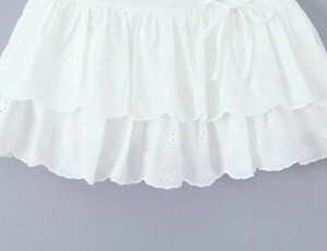 Detailed close-up of white layered ruffles with intricate floral embroidery and lace trim