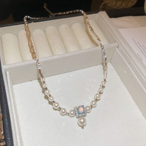 Macro detail of French style pearl necklace with blue square pendant and silver chain