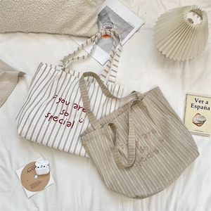 Detailed view of stripe canvas tote bags with you are so special embroidery in a soft setting