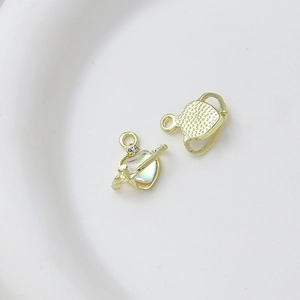 Macro detail of gold heart planet pendants with zircon and iridescent shell inlay