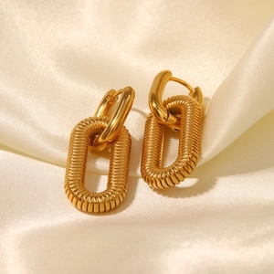 Macro detail of 18K gold plated stainless steel earrings with spiral texture on satin