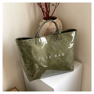 Detail view of dark green tote bag with glossy finish and white TOTE BAG text print