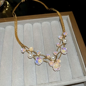 Detailed macro of iridescent flower pendant necklace with pearl accents and gold chain